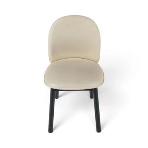 Spisestol med beige skinn, avrundet rygg og sorte bein, sett forfra