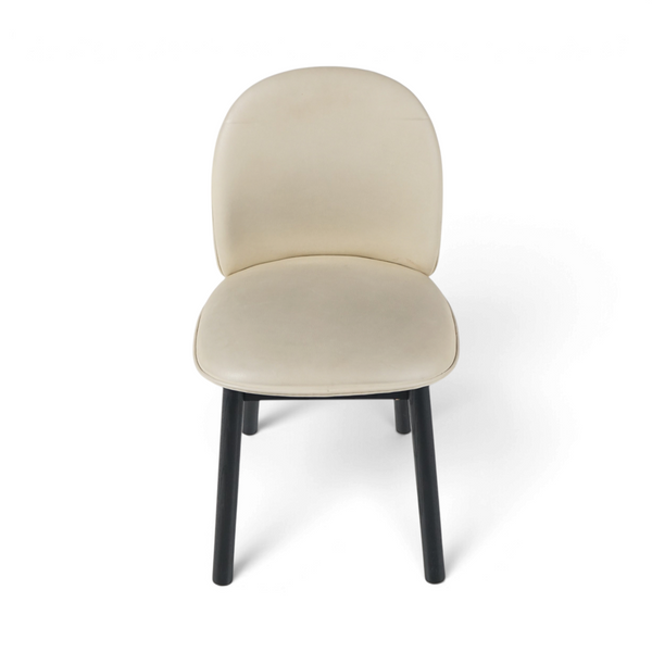 Spisestol med beige skinn, avrundet rygg og sorte bein, sett forfra