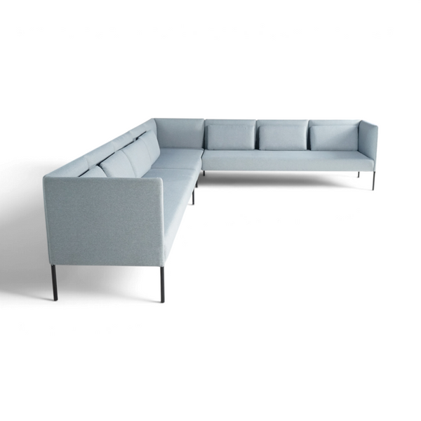 Lyseblå hjørnesofa med sorte metallbein i minimalistisk studiomiljø