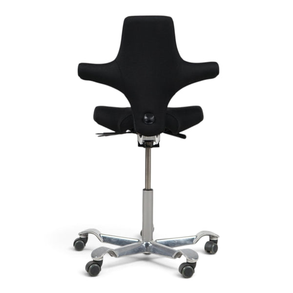 Refurnish by Loopr HÅG Capisco 8106 ergonomic office chair with a black saddle seat and silver base, rear view.